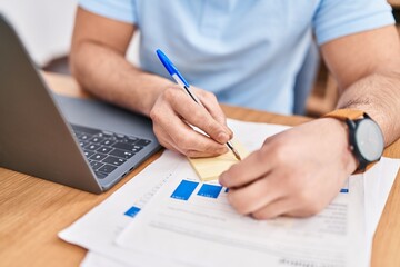 Young latin man business worker writing on reminder paper at office