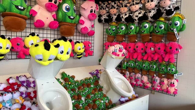 Among the toys are two toilet bowls Amusement parks in prizes that are issued for winning Many soft toys located on the shelves are the same and bright Every child and adult wants to win. 