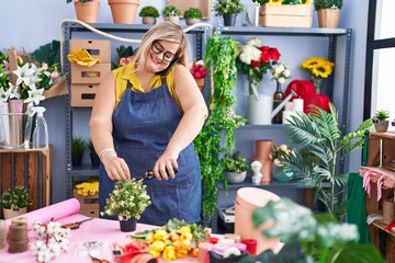 Young woman florist talking on smartphone cutting flower at florist