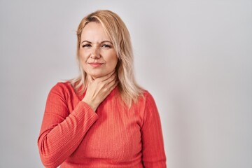 Blonde woman standing over isolated background touching painful neck, sore throat for flu, clod and infection