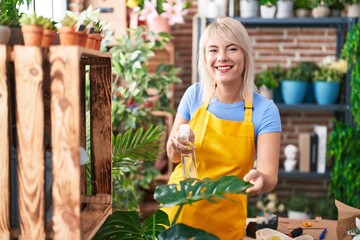 Young blonde woman florist using difusser working at florist
