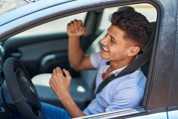 Young hispanic man smiling confident driving car at street
