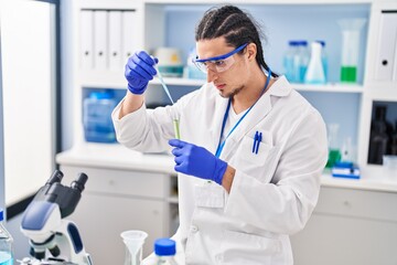 Young man wearing scientist uniform measuring liquid at laboratory