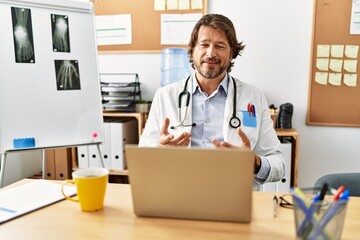 Middle age caucasian man wearing doctor uniform having video call al clinic