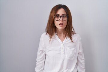 Brunette woman standing over white isolated background afraid and shocked with surprise and amazed expression, fear and excited face.