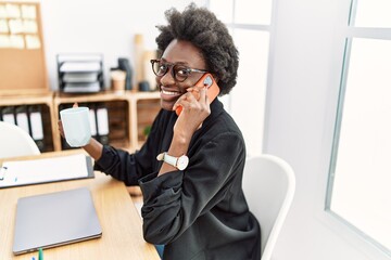 Obraz premium Young african american woman speaking on the phone drinking coffee at office