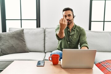 Young hispanic man with beard wearing call center agent headset working from home showing middle...