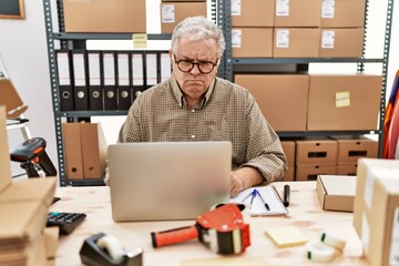 Senior caucasian man working at small business ecommerce with laptop skeptic and nervous, frowning upset because of problem. negative person.