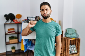 Young handsome man with beard holding shopping bags at retail shop looking at the camera blowing a kiss on air being lovely and sexy. love expression.