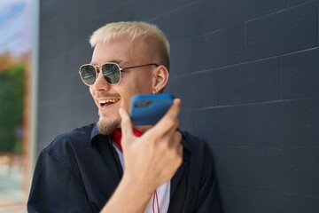Young caucasian man talking on smartphone wearing headphones at street