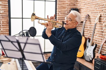 Senior man musician playing trumpet at music studio