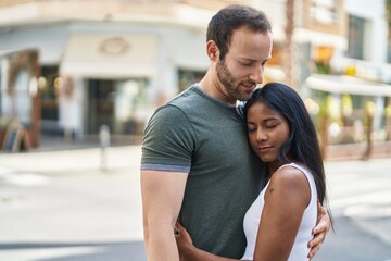 Man and woman interracial couple hugging each other at street