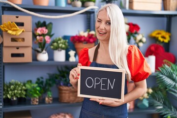 Caucasian woman working at florist holding open sign winking looking at the camera with sexy...
