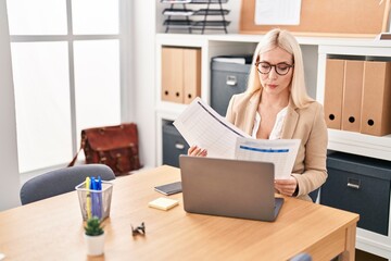 Young blonde woman business worker using laptop working and reading document at office