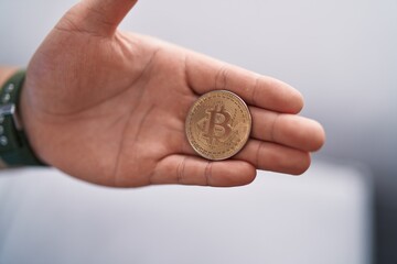 Fototapeta premium Young chinese man holding bitcoin at home