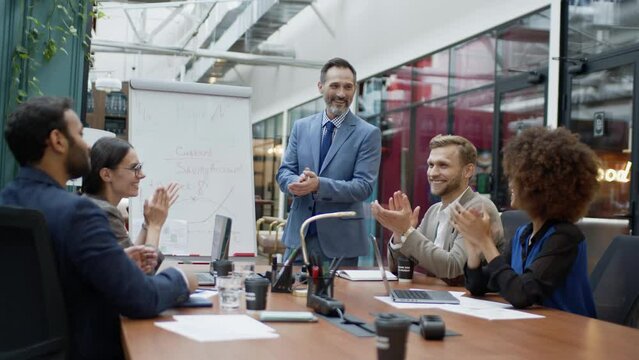Mature business coach or speaker make flip chart presentation to diverse businesspeople at meeting