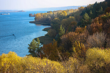 Beautiful fall landscape for postcard from a trip. Beautiful panorama of hillsides, yellow, green, brown trees with yellowing foliage. Autumn coast of a river, lake, body of water, sea. Travel Ukraine