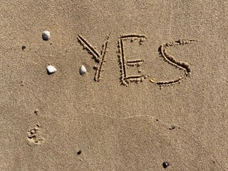 on the beach is carved with letters in the smooth sand the writing yes