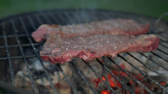 Man cooking and rotating beaf steakes on grill. 4k video footage