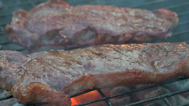 Man cooking and rotating beaf steakes on grill. 4k video footage