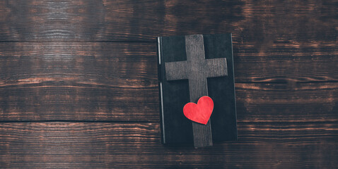 Holy Bible. On the table. Cross crucifix and red heart. The concept of God's love. On a wooden...