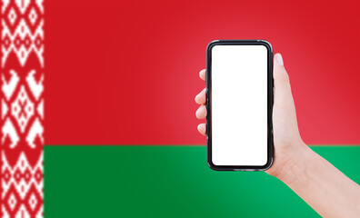 Close-up of male hand holding smartphone with blank on screen, on background of blurred flag of Belarus.