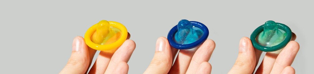 Colored condoms on a gray background, using a rubber condom to protect against venereal disease or...