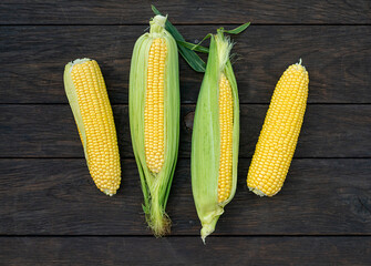 Close up view of raw corn cobs on wooden surface