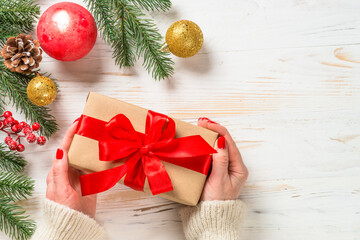 Christmas holidays greeting card. Christmas present box with red ribbon and decorations at white wooden table.