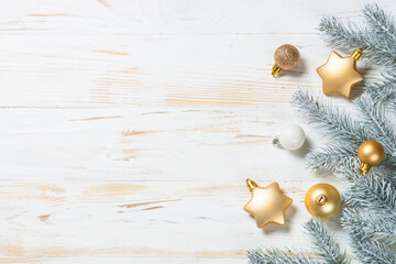 Christmas background with fir tree and golden holiday decorations. Top view at white wooden table with copy space.