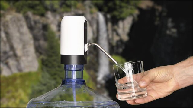Water filling with carboy and electric motor in the background with river and waterfall flowing through forests.