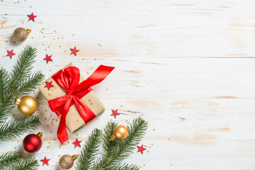 Christmas background at white. Christmas present box with red ribbon and holiday decorations. Top view with copy space.