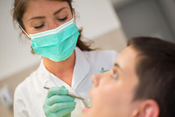Obraz na płótnie Canvas Young woman checking her teeth at the dentist clinic