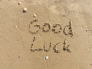 on the beach is carved with letters in the smooth sand the writing good luck