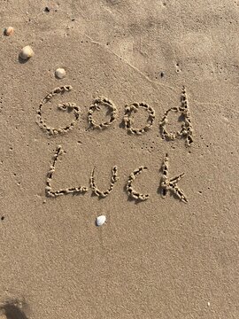 on the beach is carved with letters in the smooth sand the writing good luck