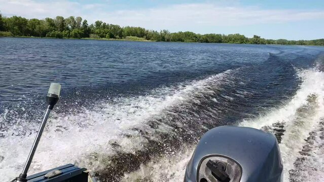 motor boat floating on the river, view of the outboard motor, wake trail on the water