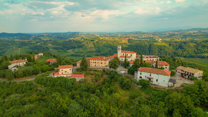 Fototapeta na wymiar AERIAL: Picturesque settlement on top of small hill in embrace of wine country