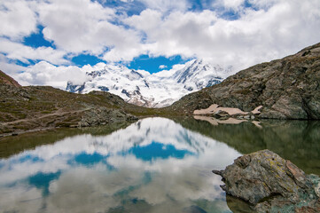 Monte Rosa (Dufourspitze) and Lyskamm covered by clouds and reflected on the Riffelsee, Swiss Alps, Valais, Switzerland