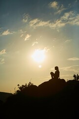 Silhouette of a girl during sunset in the mountains. The concept of victory, achievement and perfection.