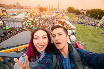 Tourist couple taking selfie photo at amusement fair and many eateries at a traditional festival on the park near bank of the Rhine river in Dusseldorf