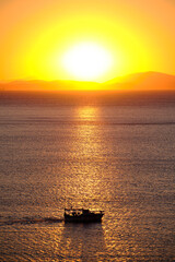 Fishing boat with fishermen on the background of the rising sun in the early morning.