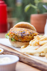 Vegan hamburger, with carrots, lentils, peppers and onions, served with french fries.