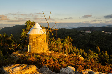 Windmill in the rays of the setting sun. Beautiful sunset in the mountains in rustic style