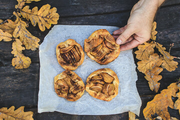 holds in hand a rustic traditional french biscuit cake with apples in autumn style, top view