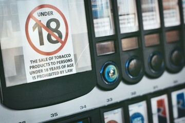 Close-up of a cigarette vending machine with an age limit sign on the front