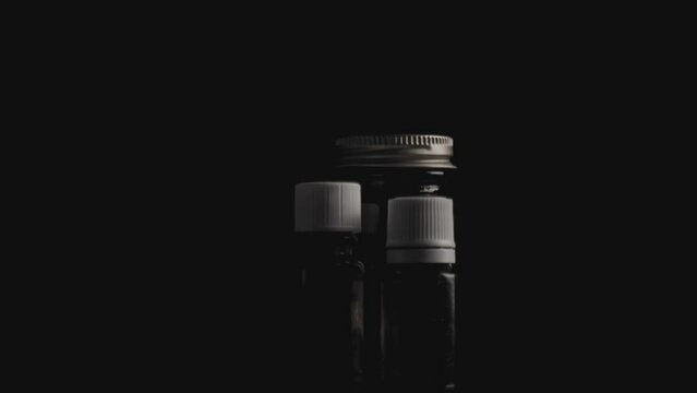two empty medication glass bottles on rotating surface against dark background