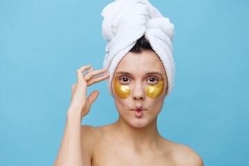  Horizontal photo, a woman with white skin on a blue background with a towel on her head and body takes care of her face and body in the evenings and relaxes. High quality photo