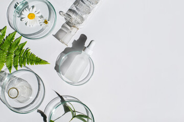 Laboratory glassware, Petri dishes,cosmetic glass bottles on white background. Natural medicine, cosmetic research, bio science, organic skin care products. Top view, flat lay, copy space. Dermatology