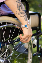 Handicapped woman sitting on the wheelchair for the disabled people , detail, hand, tattoo, wheel
