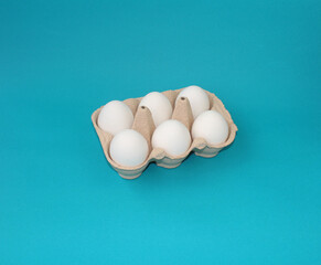 Organic chicken eggs in carton box on a blue background. Healthy fresh food .